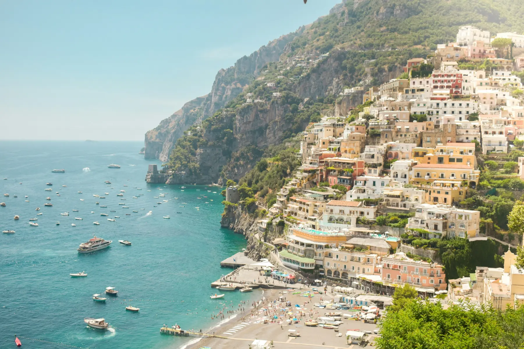 Casas de colores de Positano cayendo hacia el mar, con barcas en la bahía